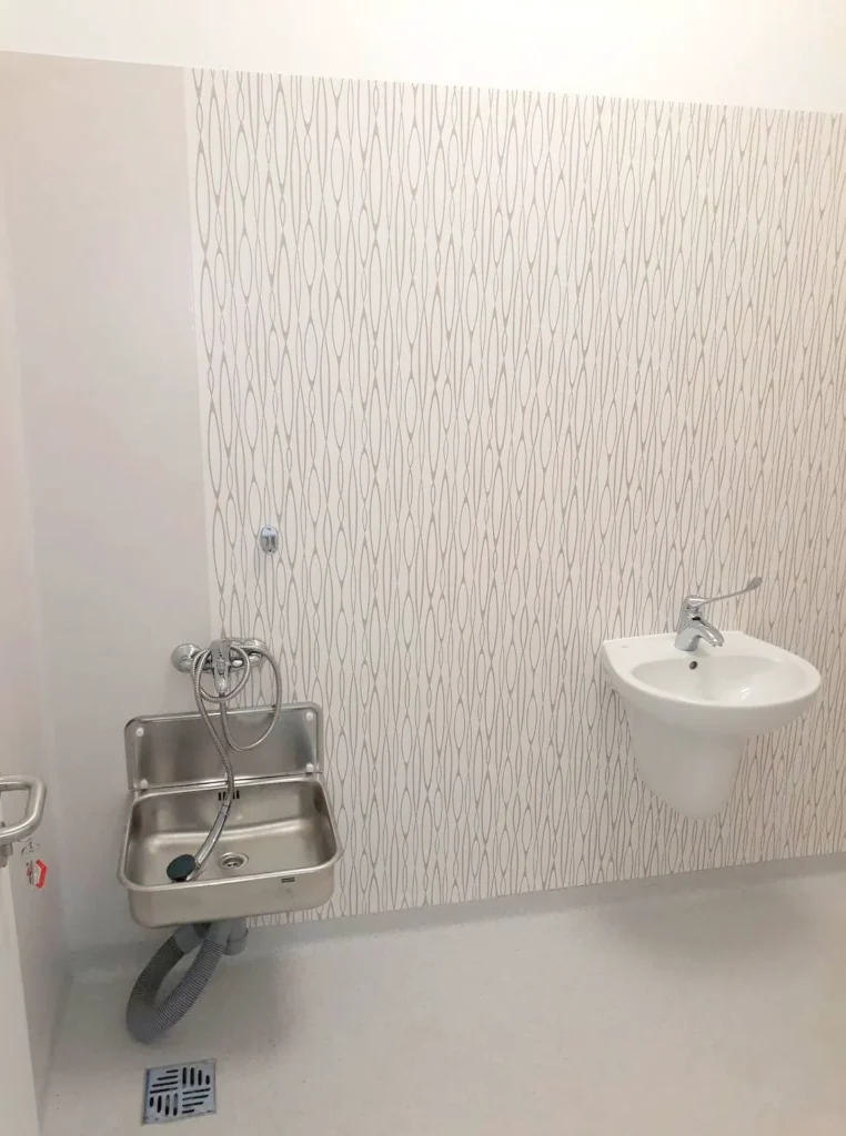 Stalowy zlew i ceramiczna umywalka na tle dekoracyjnej okładziny ściennej